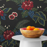 Our Lanai wallpaper is inspired by the rich tradition and exuberant patterns of Hawaiian shirts, with a twist. Highly durable, fade resistant, and made in the USA. This wallpaper features red flowers with green and blue leaves on a black background and was created in collaboration with The Aesthetics of Joy.