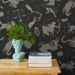 Our In the Stars wallpaper is inspired by Urania’s Mirror, a 19th-century set of astrology charts. This hand-drawn pattern evokes the mysterious motion of celestial bodies. This wallpaper features gray and gold motifs on a black background and was designed by Julia Rothman.