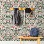 Nora (Blush) wallpaper features a garden of bees, birds, strawberries, and flowers in green, blue and red on a pink background.