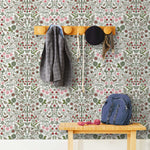 Nora (Leaf) wallpaper features a garden of bees, birds, strawberries, and flowers in shades of green, pink and taupe on a white background.