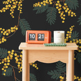 Wallpaper with yellow acacia flowers and green leaves on a soft black background | Schoolhouse + Hygge & West