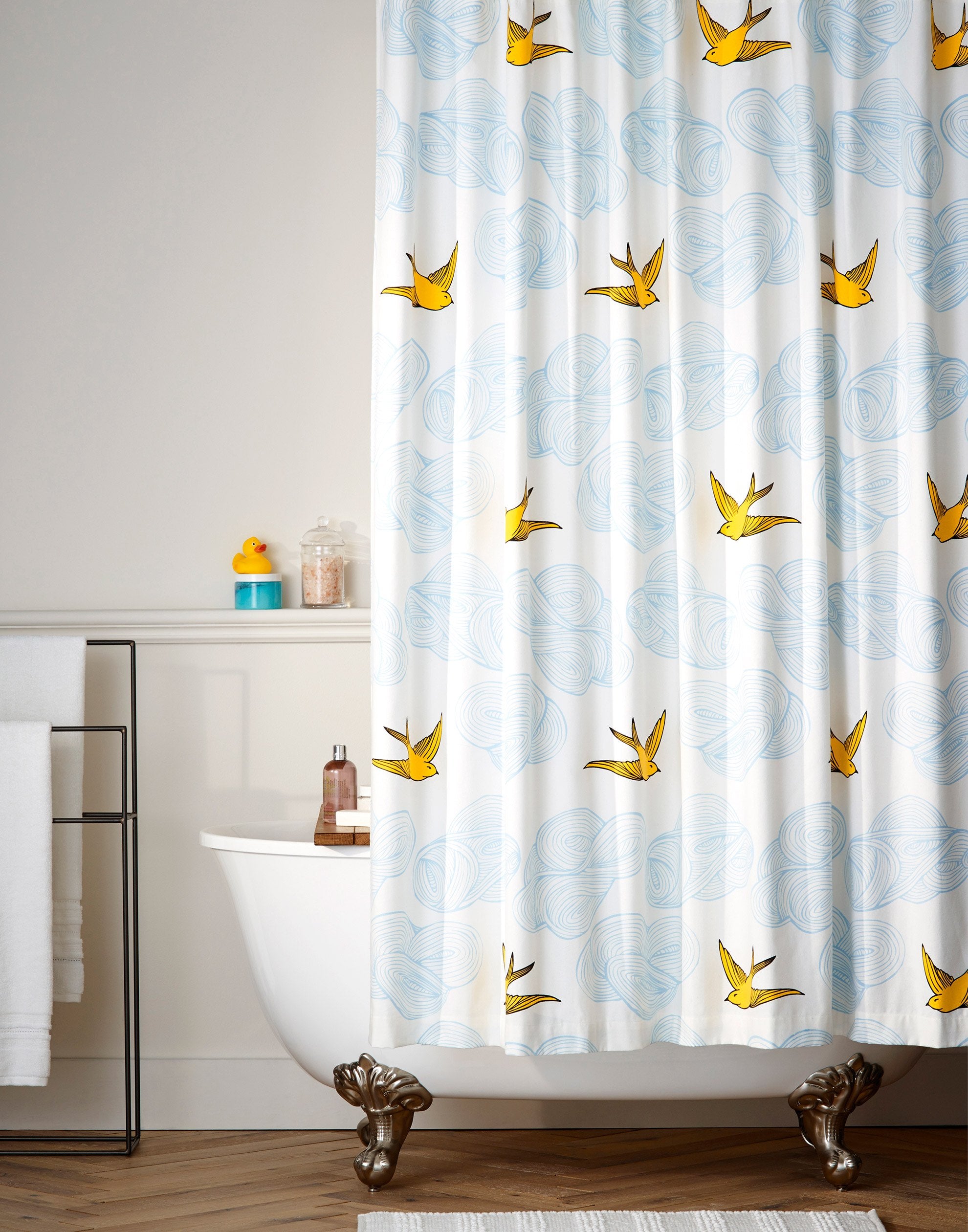 Daydream (Sunshine) Shower Curtain features a pattern of flying birds and floating clouds in yellow and blue on white