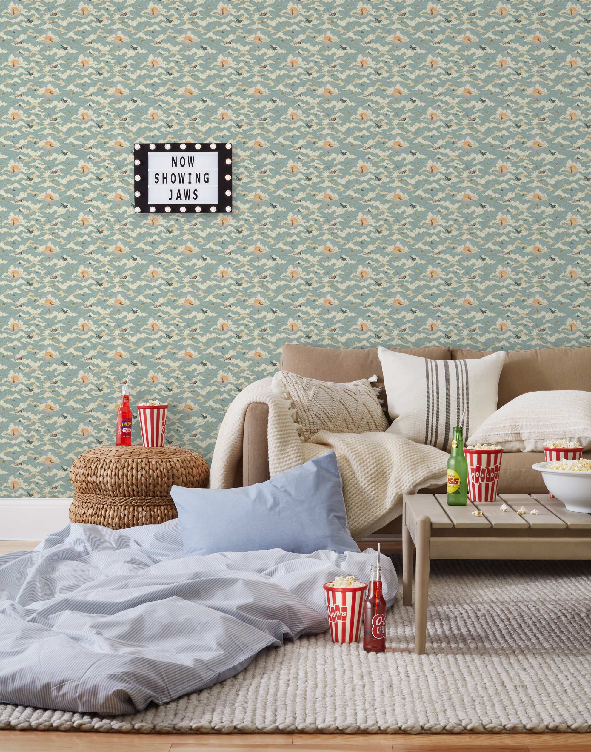 Amity Sunset (Sky) Wallpaper with dusty blue, cream and orange illustrations depicts scenes from the iconic movie Jaws and was created in collaboration with Universal | Hygge & West